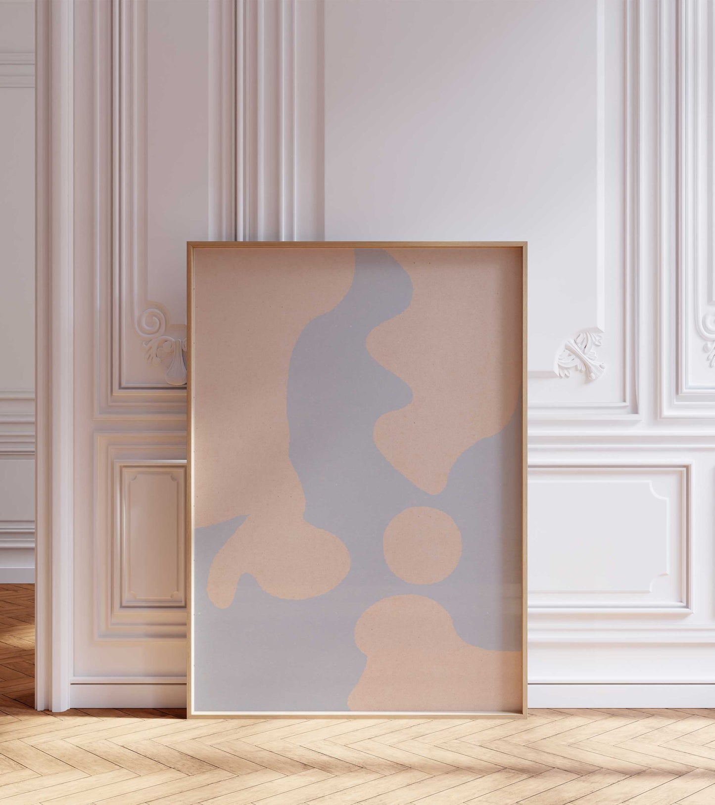 Abstract poster framed in a wooden frame, stands in a room with white walls and wooden floor